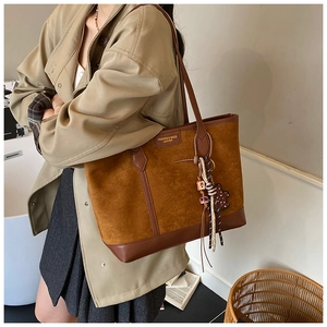 Dettaglio della borsa tote marrone vintage con patchwork in pelle scamosciata e orsetto