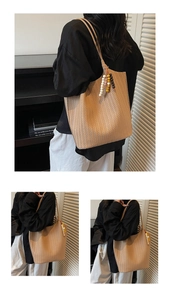 Detail of khaki woven tote bag with V-shaped texture and retro wooden bead pendant charm