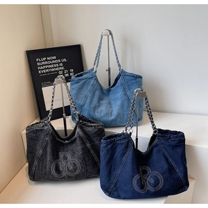Three denim tote bags with metallic chain straps and embroidered logos in a tiered display