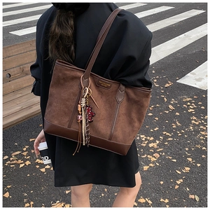 Dettaglio di una grande borsa tote in pelle scamosciata marrone con ciondoli colorati