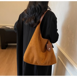 Detail view of brown suede hobo bag with sleek leather strap and small side pouch