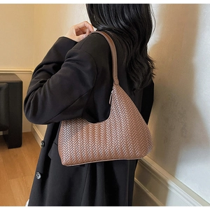 Détail de la texture en cuir tressé marron d'un sac sous les bras vintage chic