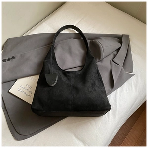 Détail de la texture d'un sac hobo en daim noir avec bandoulière sur fond esthétique