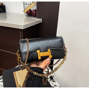 Détail du cuir grainé noir et boucle en H dorée sur un sac à main chic à chaîne