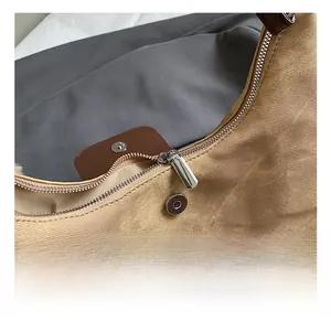 Detail of khaki tote bag showing silver zipper closure and premium brown leather magnetic snap