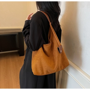 Close-up of caramel suede tote bag featuring a heart-shaped leather accent and soft texture