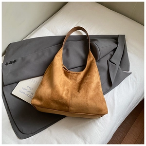 Détail d'un sac hobo en daim marron avec couture verticale sur literie blanche