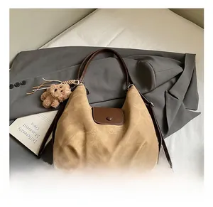 Detail of canvas hobo tote with leather handle and cute bear plush charm accessory