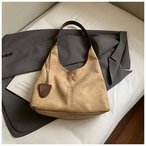 Détail du sac fourre-tout en daim kaki avec bandoulière marron et breloque bouclier chic