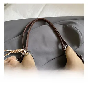 Close-up of khaki canvas tote bag handles with brown leather trim and bear charm