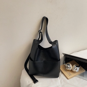 Detail of black pebbled leather bucket bag with silver hardware for daily commute