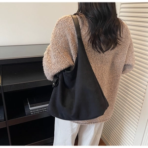 Detail view of the black minimalist hobo tote bag worn as an underarm shoulder bag