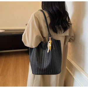 Detail of black woven tote bag with colorful beads on a trench coat model
