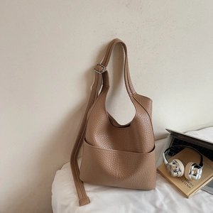 Detail of tan pebble leather shoulder bag showing the large front pocket and silver buckle