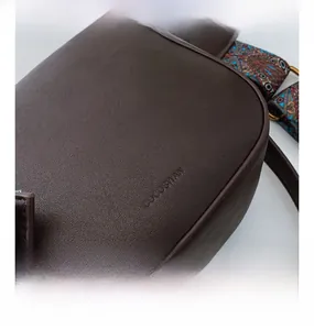 Detail of dark brown pebble leather texture and retro bohemian strap on the crossbody bag