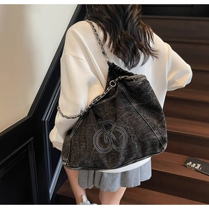 Detail view of large dark grey denim tote bag with chain strap and white embroidery