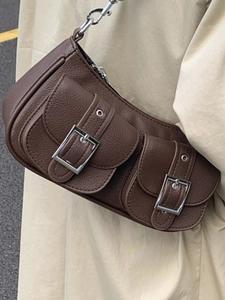 Dunkelbraune Ledertasche mit Schnallen, getragen von einem Modell im Trenchcoat