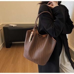 Detail shot of deep brown woven tote bag showing texture and stylish beaded pendant