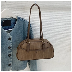 Détail d'un sac sous les aisselles marron avec texture bois et ferrures dorées