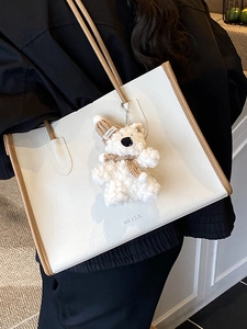 Minimalist white tote bag with brown trim, featuring a teddy bear charm for women