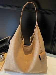 Modern camel suede hobo tote bag with heart charm shown in a minimalist office setting