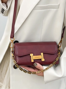 Sac bandoulière en cuir bordeaux mat avec boucle H dorée et chaîne sur blazer blanc