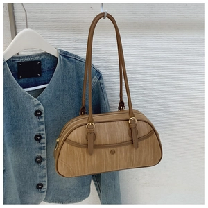 Détail du sac sous le bras marron clair avec texture grain de bois et anneaux dorés