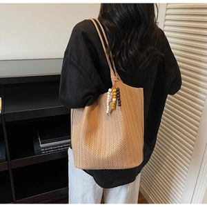 Detail of light brown woven leather tote bag with colorful beaded tassel charm