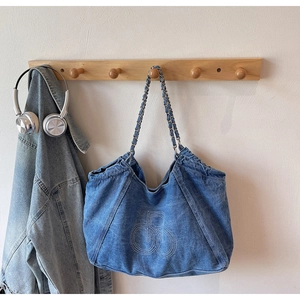 Detail of blue denim canvas tote bag featuring chain strap and round stitched logo design