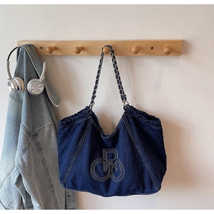 Detail of dark blue denim tote bag featuring white contrast stitching and chain shoulder strap