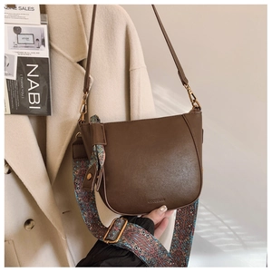Detail of vintage brown bucket bag with bohemian printed wide strap and leather strap