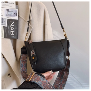 Detail of black faux leather bucket bag featuring a vibrant ethnic style woven strap