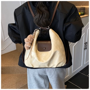 Detail view of large pleated beige tote bag with brown flap and cute bear pendant