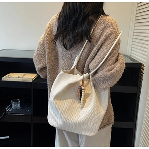 Detail of white woven tote bag with retro bead pendant on minimalist shoulder strap