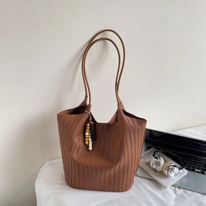 Detail shot of brown woven leather tote bag with stylish wooden bead charm