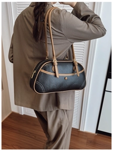 Détail d'un sac à bandoulière tressé noir avec lanières en cuir marron sur un blazer