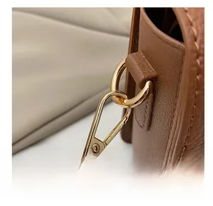 Detailed close-up of premium golden metal hook and brown lychee grain leather texture