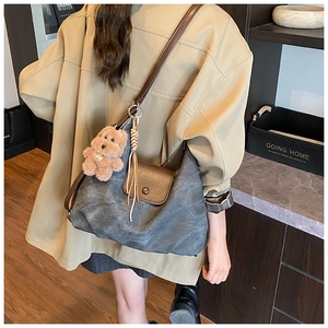 Detailed close-up of dark grey canvas tote with brown leather flap and cute bear pendant