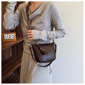 Detail view of dark brown leather bucket bag with decorative ethnic woven shoulder strap