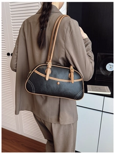 Détail du sac sous le bras tressé noir avec garniture en cuir marron porté par un mannequin