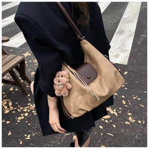 Detail view of khaki pleated tote bag with plush puppy charm and brown leather trim