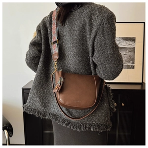 Detail of brown leather saddle bag with interchangeable vintage patterned wide strap