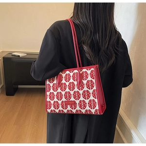 Detail of red festive tote bag featuring traditional double happiness patterns and leather handle