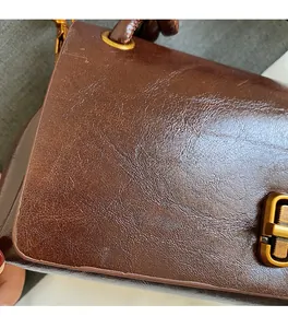Detail of dark brown oil wax leather texture and vintage gold buckle on handbag