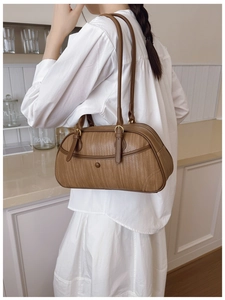 Détail d'un sac à bandoulière marron à texture tressée avec boucles métalliques décoratives