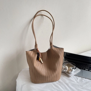 Detail of hand-woven tote bag in dark khaki leather with boho beaded pendant charm