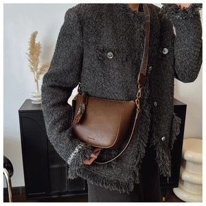 Detail of a brown leather bucket bag with wide floral strap and scarf accent