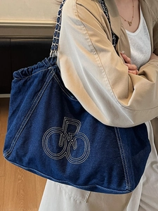 Large dark blue denim tote bag with white stitching logo and chain strap for women