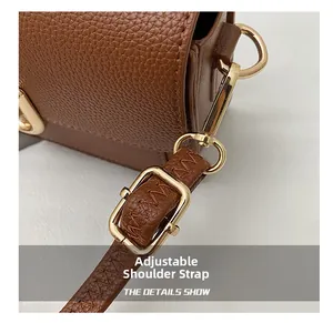 Close-up of adjustable brown leather shoulder strap with golden metal buckle and stitching