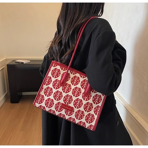 Detail of red festive tote bag with traditional pattern worn over a black winter coat